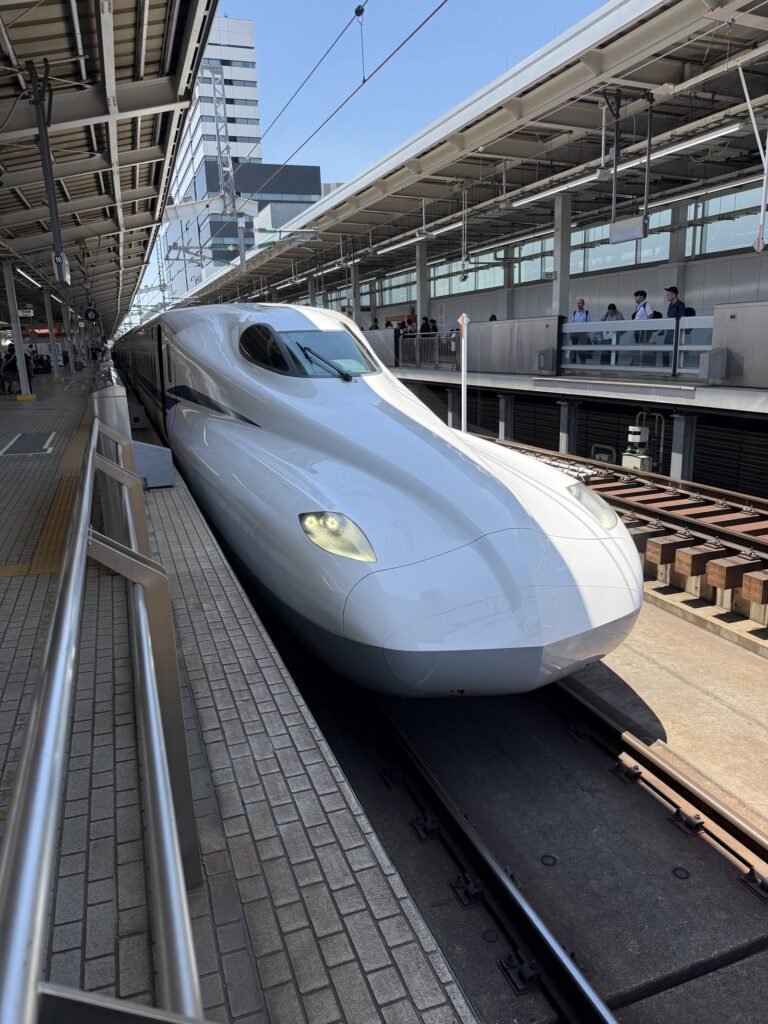 กลไกค่าโดยสารรถไฟญี่ปุ่น: อธิบายค่าโดยสารพื้นฐาน + ตั๋วรถไฟด่วนพิเศษ (2026) A Shinkansen bullet train at Shin-Osaka Station